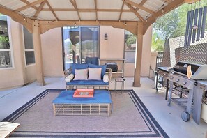 Eine Außenpatio mit überdachter Sitzgelegenheit, einem Grill und Blick auf die umliegende Landschaft.