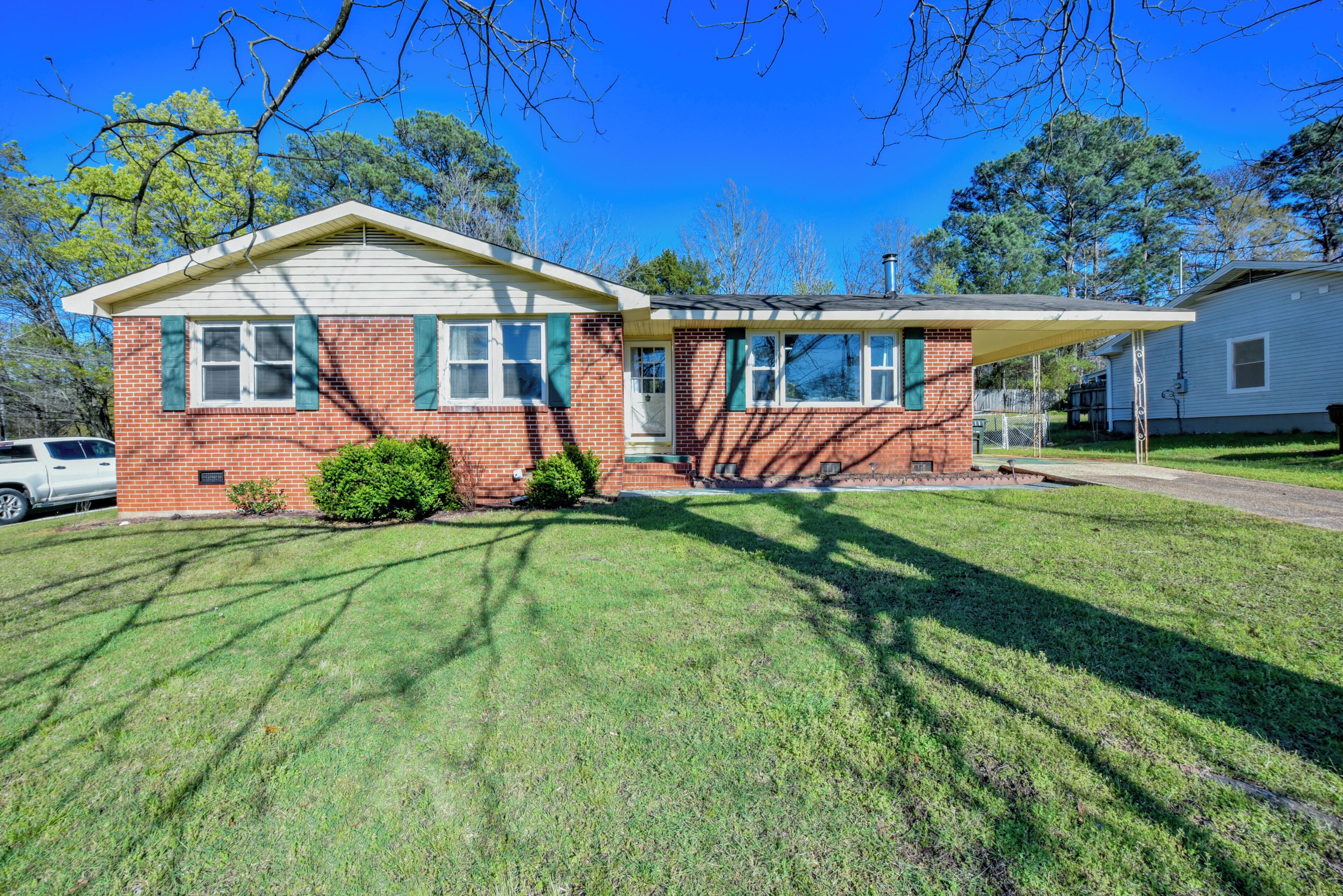 A two-story house with a brick facade, a covered porch, and a well-maintained lawn.