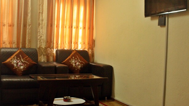 A living room with a sofa, a coffee table, and a television mounted on the wall. - Hotel The Greatwall (Kathmandu)