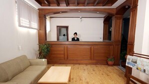 Un espace d’accueil comprenant un comptoir en bois, un canapé, une table basse et des plantes en pot.