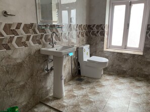 A bathroom with a sink, toilet, and a window. - Potala Tourist Home (Kathmandu)