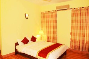 A hotel room with a bed, a lamp, curtains, and an air conditioning unit. - Potala Tourist Home (Kathmandu)