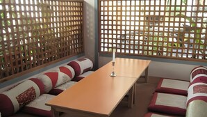 A room with a wooden table, two sofas with patterned cushions, and a lattice partition. - Potala Tourist Home (Kathmandu)