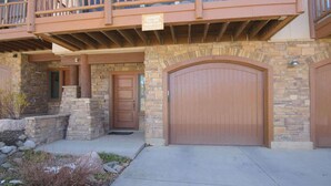 A two-story building with a stone facade, a wooden balcony, and a large garage door. - Updated Treasury Point condo, garage, hot tub! (Crested Butte)