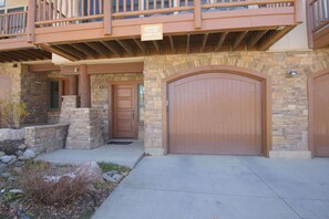 A two-story building with a stone facade, a wooden balcony, and a large garage door. - Updated Treasury Point condo, garage, hot tub! (Crested Butte)