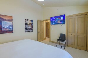 A hotel room with a large bed, a flat-screen TV mounted on the wall, and two doors. - Updated Treasury Point condo, garage, hot tub! (Crested Butte)