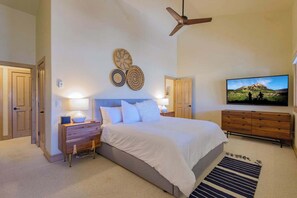 A bedroom with a bed, bedside tables, a TV, and a ceiling fan. - Updated Treasury Point condo, garage, hot tub! (Crested Butte)
