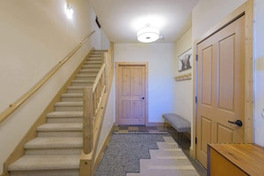 A staircase with wooden handrails, carpeted steps, and a patterned rug at the bottom. - Updated Treasury Point condo, garage, hot tub! (Crested Butte)