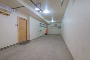 A narrow hallway with a wooden door, a light fixture, and a shelf with various items. - Updated Treasury Point condo, garage, hot tub! (Crested Butte)