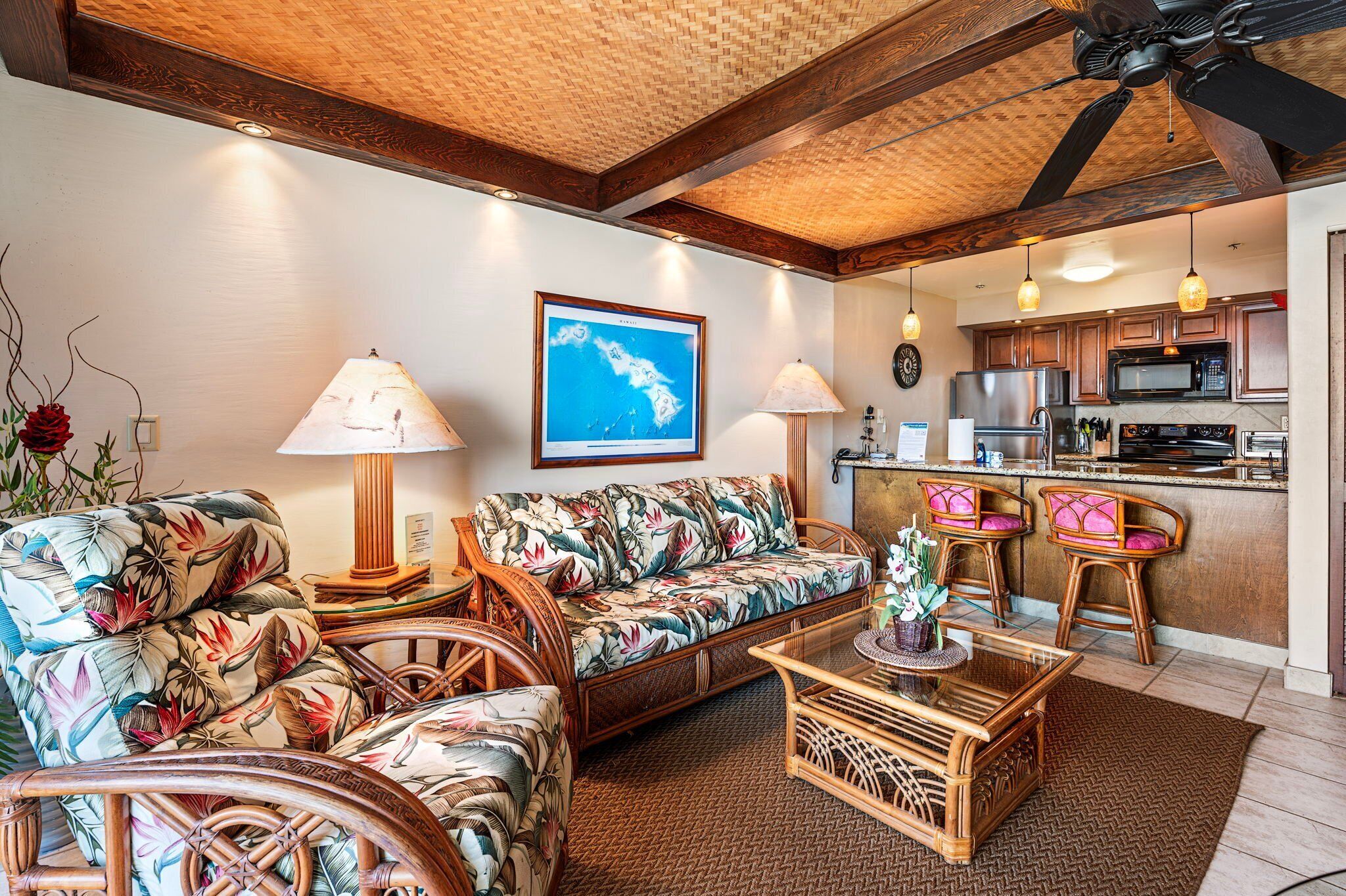 A living room with a sofa, chairs, a coffee table, and a kitchen area with a microwave and refrigerator.