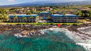 A resort with multiple buildings, clear blue waters, and a rocky shoreline. - Easy Walk to Town Ocean Front AC & Wifi - Vrkcv (Kailua-Kona)