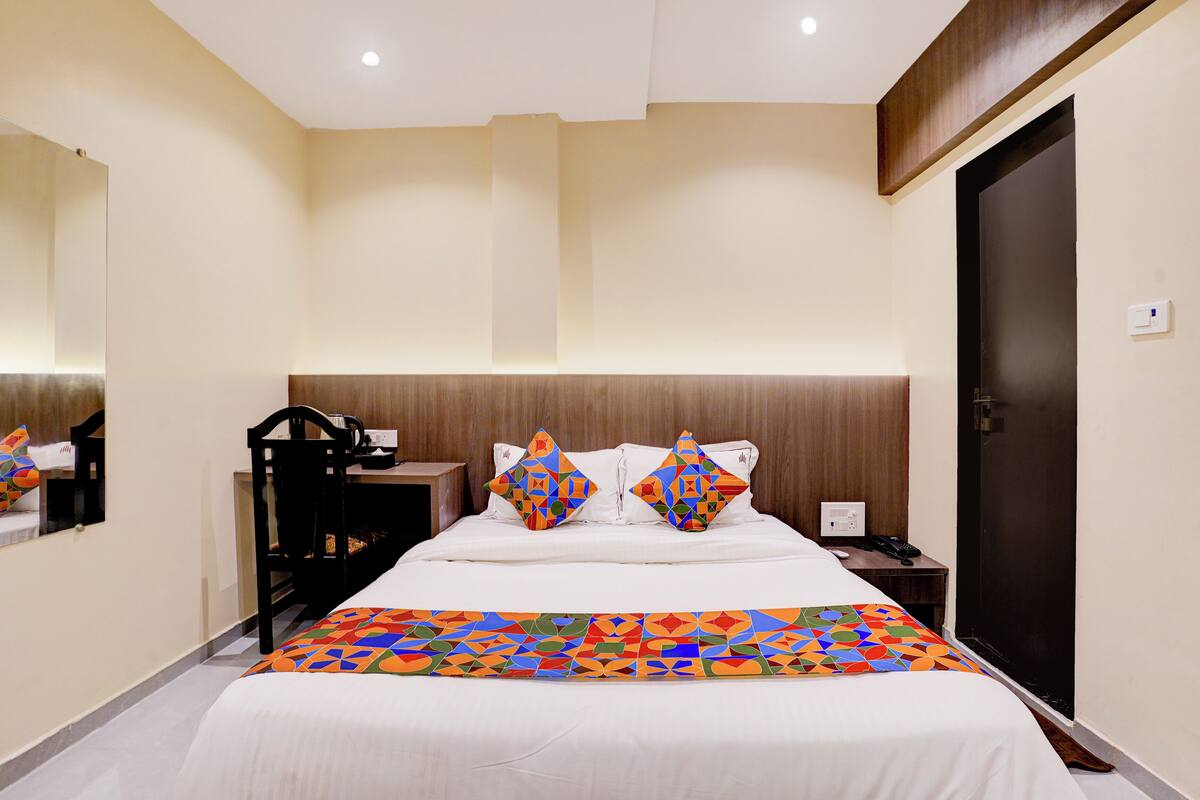 A hotel room with a bed, a desk, a chair, and a door.