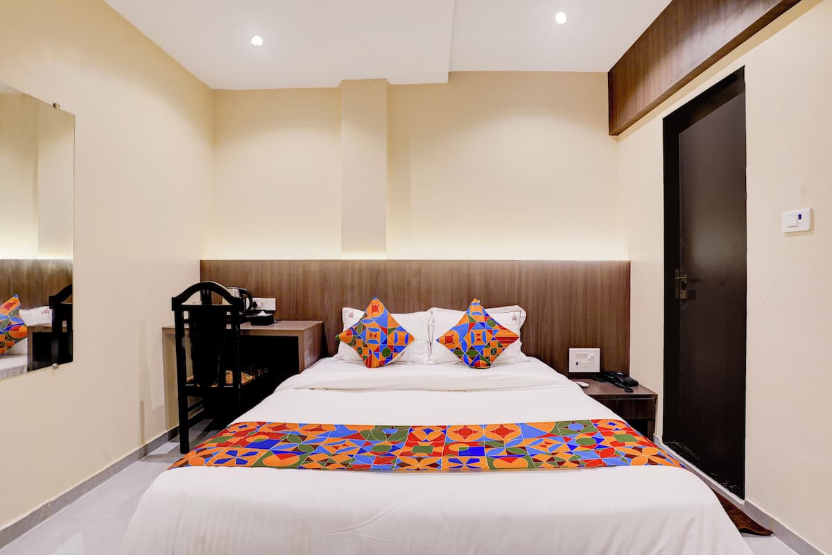 Una habitación de hotel con una cama, un escritorio, una silla y una puerta.
