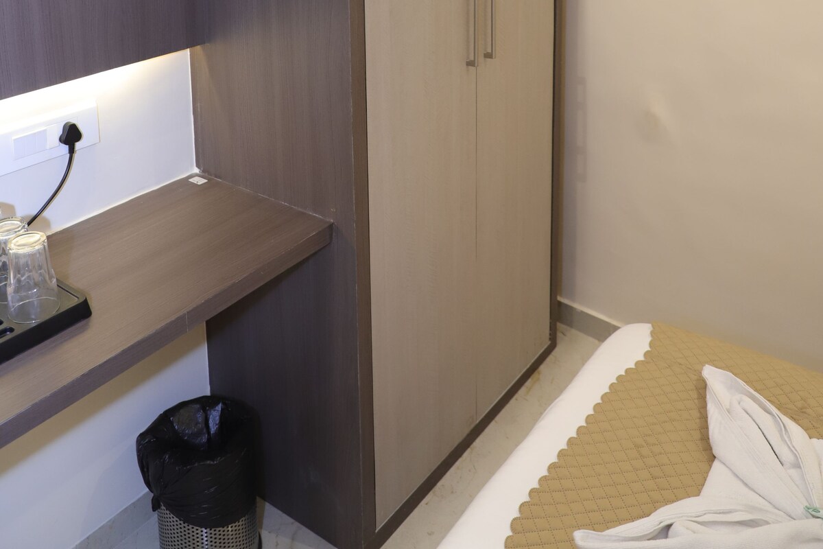 Una habitación con armario, escritorio con lámpara y cama con toalla.