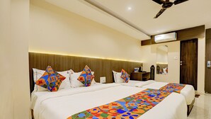 Una habitación de hotel con una cama grande, un ventilador de techo, un equipo de aire acondicionado y una mesita de noche con lámpara.
