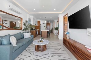 A modern living room with a sofa, coffee table, and a TV mounted on the wall. - Boho 2 BR Condo - Dowtown - Rooftop Pool - Jacuzzi (Puerto Vallarta)