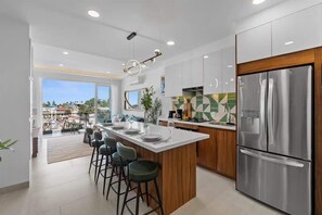 A modern kitchen with a central island, stainless steel appliances, and a view to the outside. - Boho 2 BR Condo - Dowtown - Rooftop Pool - Jacuzzi (Puerto Vallarta)