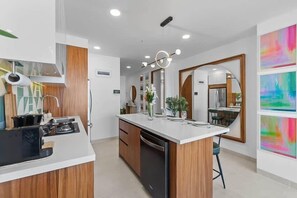 A modern kitchen with a central island, wooden cabinets, and a built-in dishwasher. - Boho 2 BR Condo - Dowtown - Rooftop Pool - Jacuzzi (Puerto Vallarta)