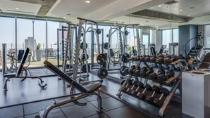 A modern gym with various weightlifting equipment, cardio machines, and dumbbells. - Cozy 1-bedroom apartment with AC in marvelous Raleigh (Raleigh)