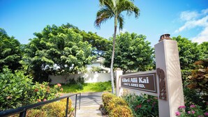 Un sentiero conduce a un edificio con un cartello che riporta 'Kihei Alii Kai 2387 S. KIHEI RD'.
