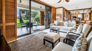Ein geräumiger Wohnbereich mit einem großen Schiebeglastür, die auf eine Terrasse führt, einem Deckenventilator und einem modernen Interieur.