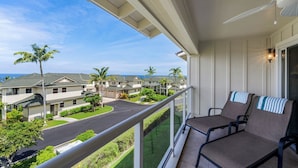 A balcony with two chairs, overlooking a residential area with houses and palm trees. - Updated Townhome Ocean View Private BBQ & Lanai - Vrkcv (Kailua-Kona)