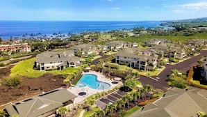 A residential area with a swimming pool surrounded by houses, a clear view of the ocean, and a well-maintained landscape. - Updated Townhome Ocean View Private BBQ & Lanai - Vrkcv (Kailua-Kona)