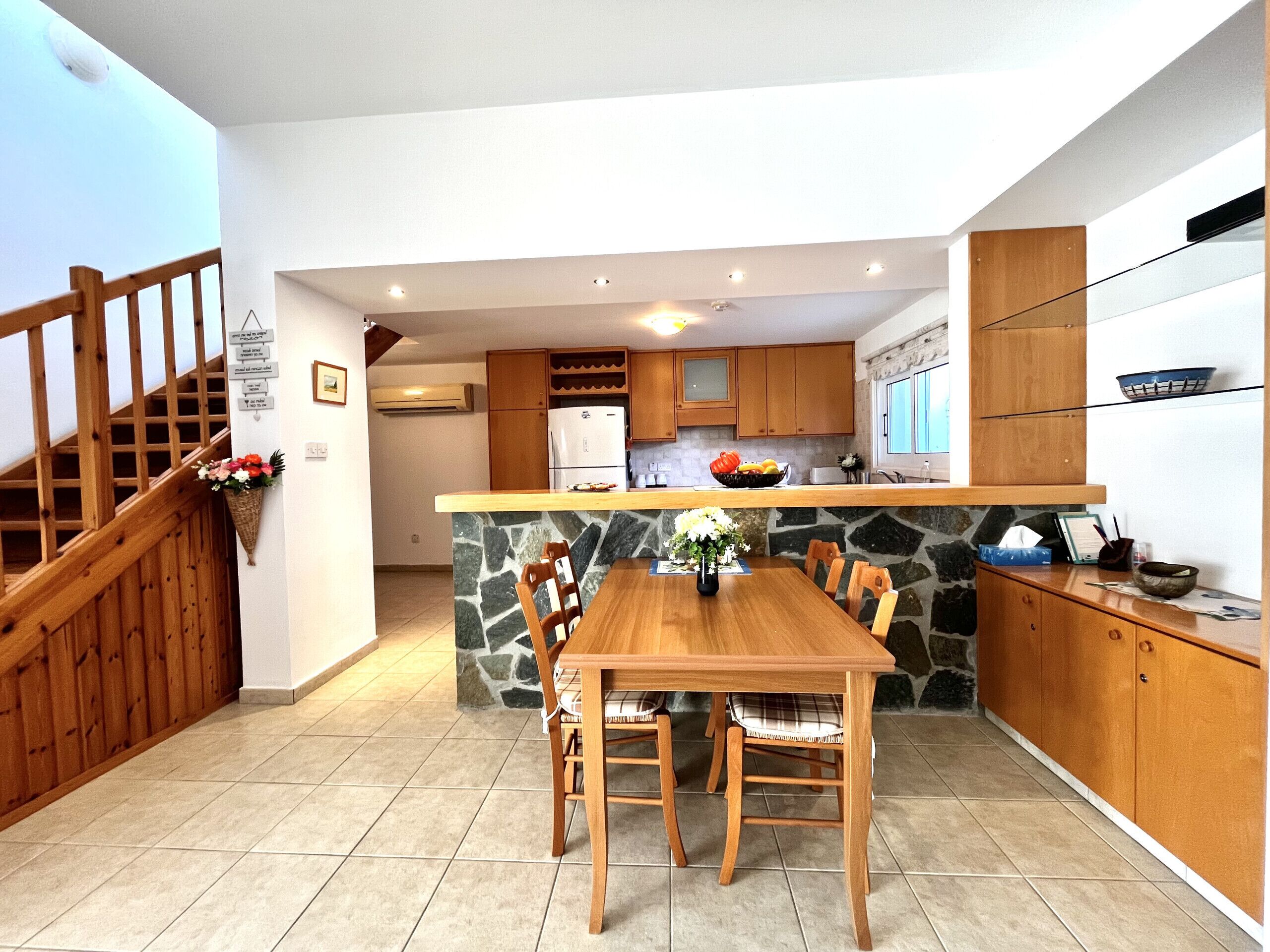 A modern kitchen with a central island, wooden cabinets, and a stone backsplash.