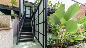 A staircase with black railings leading to a covered area with potted plants. - w Attractive 2BR w Balcony in Poblado (Medellín)