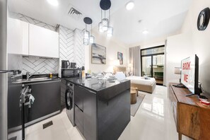 A modern kitchen with a central island, built-in appliances, and pendant lighting. - Stayshort - Studio in JVC Sleeps 2 With City Views (Dubai)