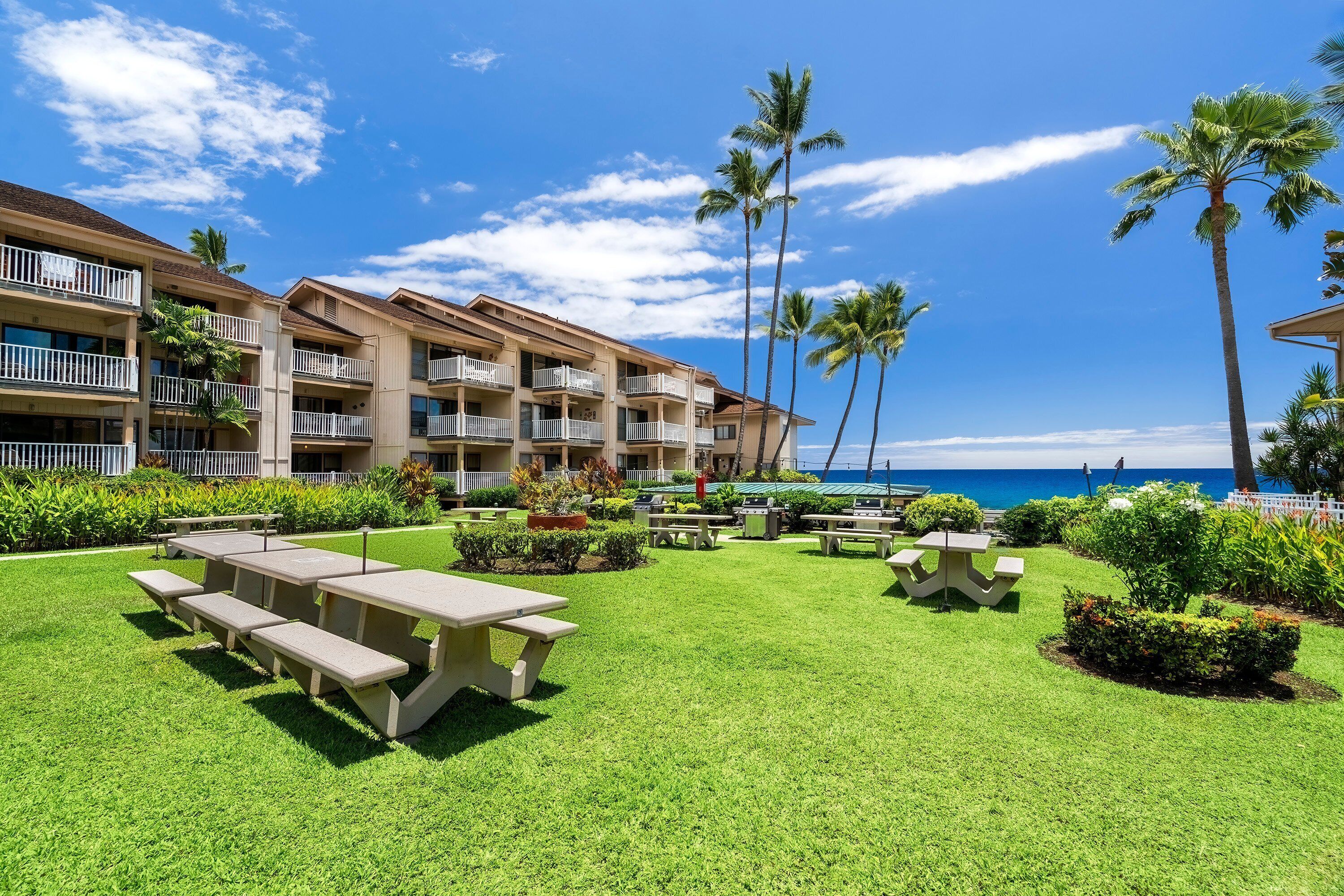 A resort with multiple-story buildings, outdoor seating areas, and palm trees.