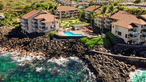 A resort with multiple buildings, a swimming pool, and a rocky shoreline. - Ocean Front Fantastic Views Corner Unit - Vrkcv (Kailua-Kona)