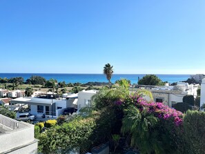 Un quartier résidentiel situé sur la côte, avec des bâtiments modernes, un ciel d’un bleu éclatant et une vue sur la mer.