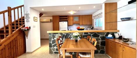 A modern kitchen with a central island, wooden cabinets, and a stone backsplash.
