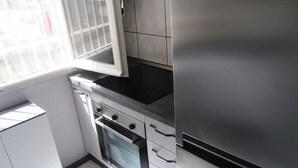 A modern kitchen with stainless steel appliances, white cabinetry, and a window providing natural light. - In the heart of the forest stands Pachamama, 900 m above sea level detached cottage (Bajardo)