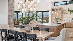 Een moderne keuken met een groot eiland, houten kastjes en uitzicht op bergen.