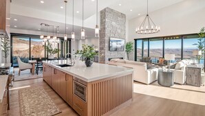 Een moderne keuken met een centraal eiland, hangende lampen en een accentmuur van steen.