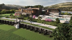 Een modern hotel met een zwembad, terras en uitzicht op het omliggende landschap.