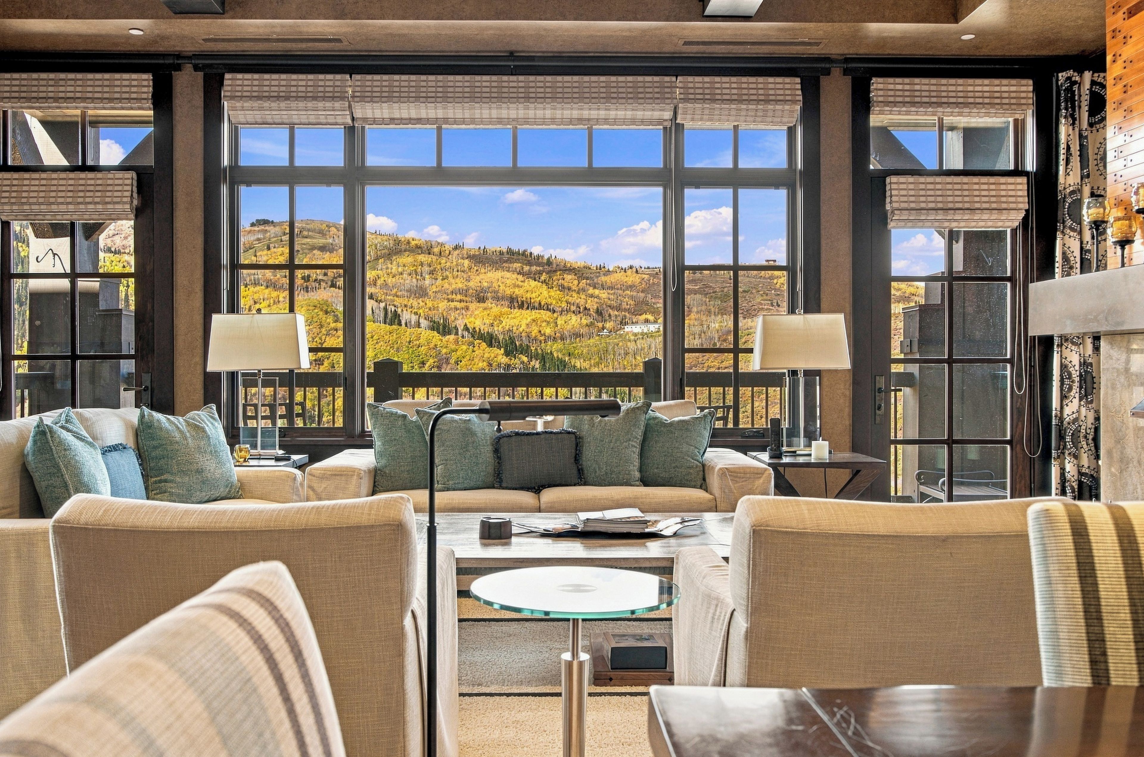 A spacious living area with a large window offering a view of a hilly landscape.