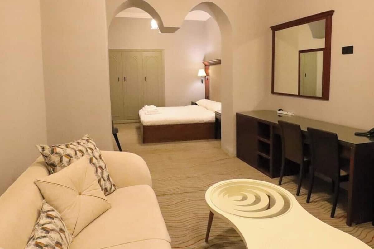 Een hotelkamer met een slaapbank, bureau, bed en spiegel.