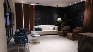 A modern living room with a white sofa, blue chairs, and a small round table.