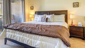 A neatly made bed with a brown and white striped comforter, a wooden headboard, and a nightstand with a lamp and a tissue box. - Pool & Tennis Access! Condo in Central Scottsdale (Scottsdale)