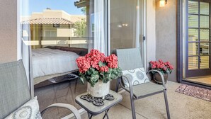 A balcony with a bed, two chairs, and a potted plant. - Pool & Tennis Access! Condo in Central Scottsdale (Scottsdale)