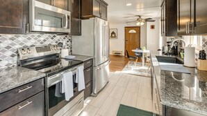 Une cuisine moderne dotée d’appareils électroménagers en acier inoxydable, de meubles de rangement en bois foncé et d’un dosseret carrelé.