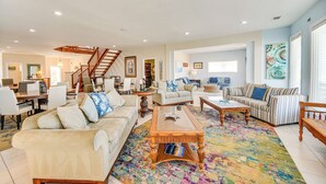A spacious living room with a staircase, a dining area, and a kitchen in the background. - Blue Dolphin, Oceanfront Views! Sandbridge Home (Virginia Beach)