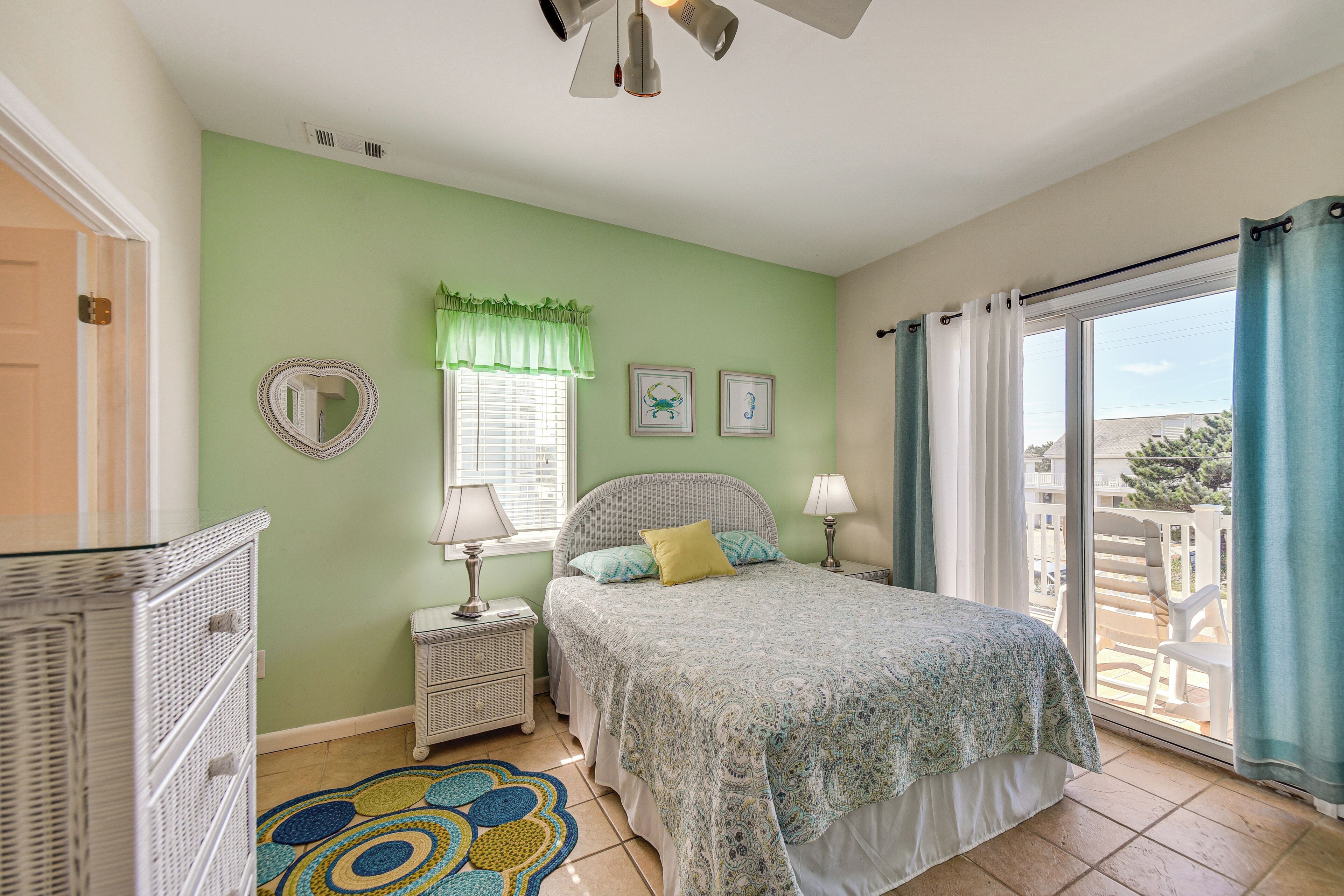 A bedroom with a bed, nightstands, a mirror, and a window with curtains.