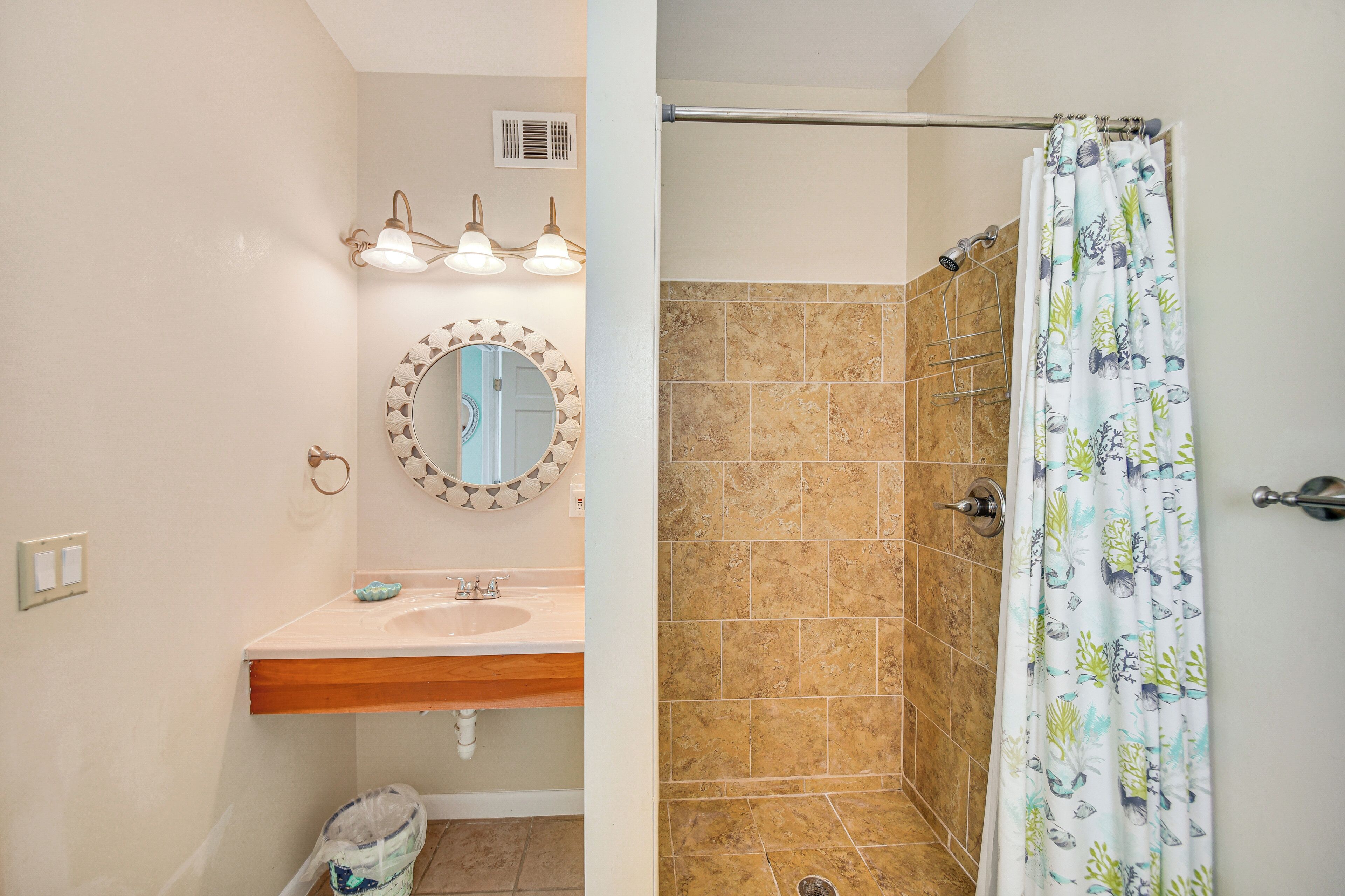 A bathroom with a sink, mirror, and shower.
