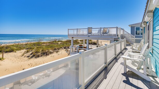 A beachside deck with a glass railing, beach chairs, and a view of the ocean. - Blue Dolphin, Oceanfront Views! Sandbridge Home (Virginia Beach)