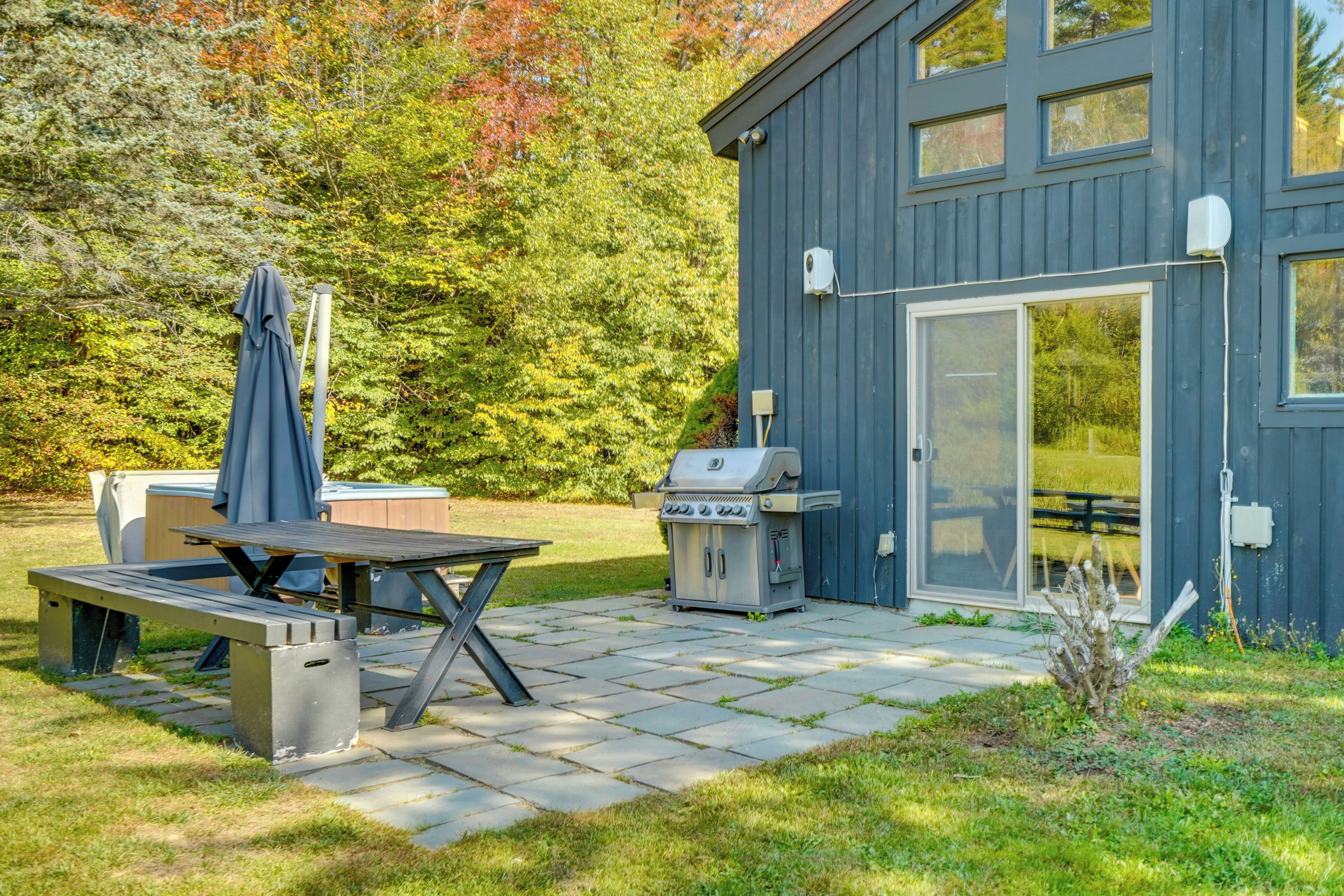 An outdoor patio with a grill, a table, and a covered seating area.