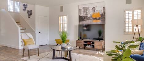 Amplia sala de estar con una escalera, un televisor de pantalla plana y una zona de comedor.
